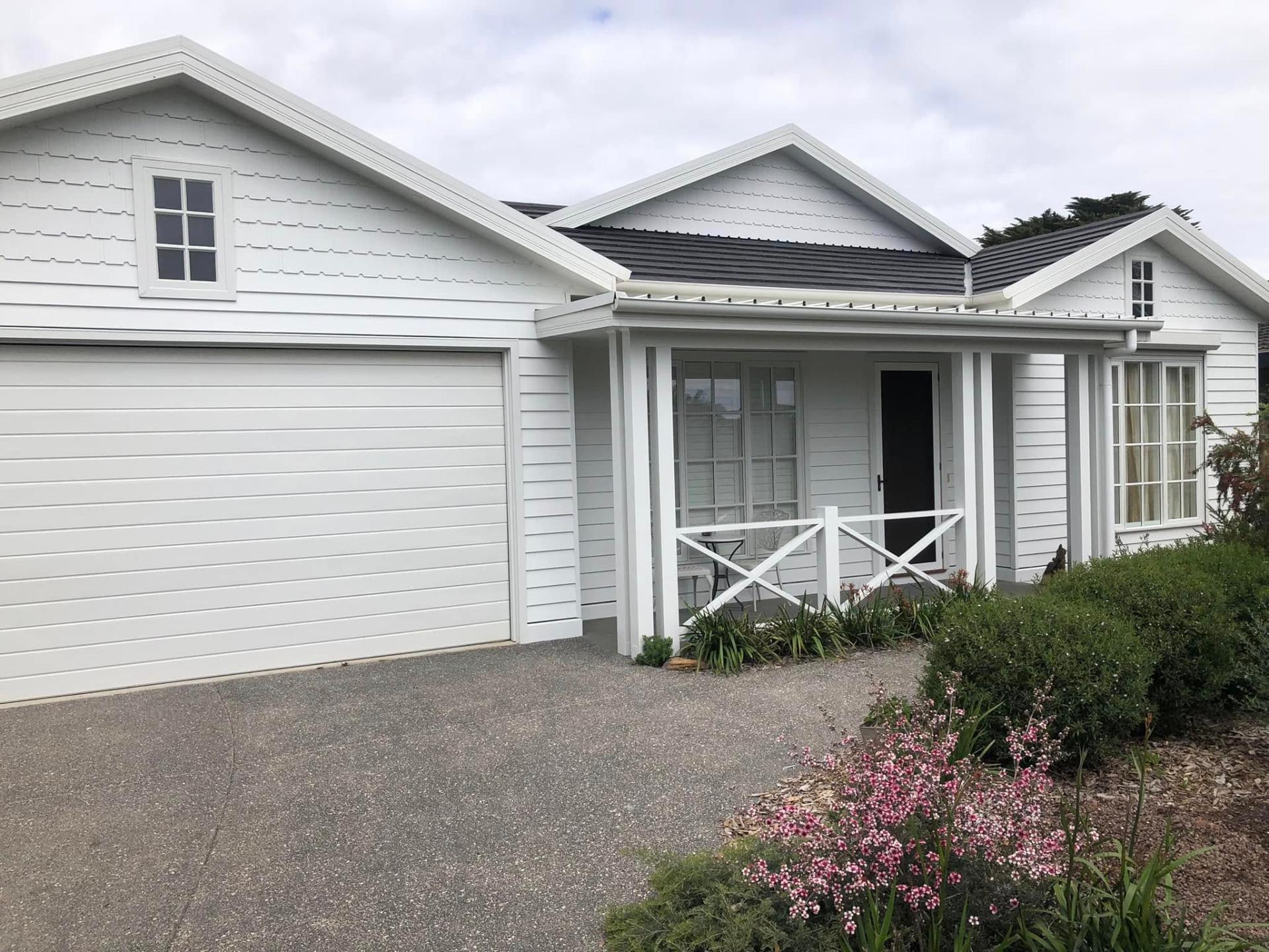 Pale weatherboard exterior repainted in a bold deep navy with fresh white trim for real street presence. — before
